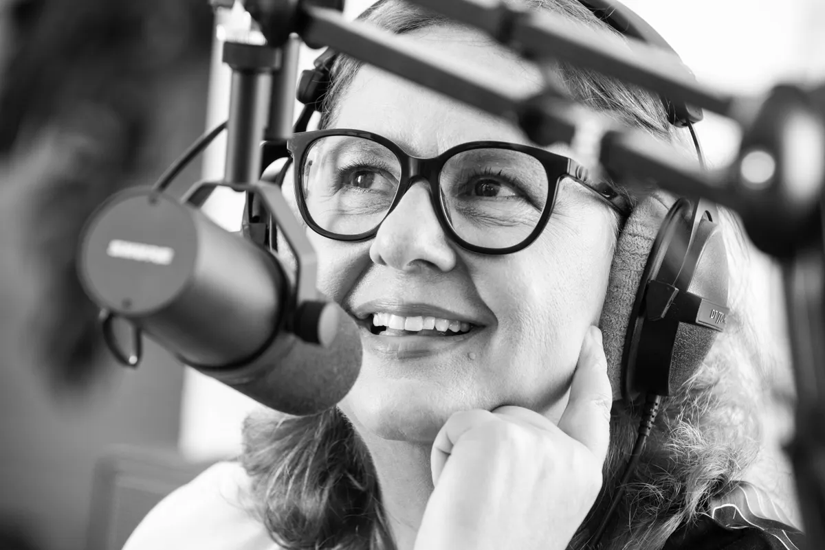 Frau mit Kopfhörern spricht in ein Podcast-Mikrofon während einer Aufnahme