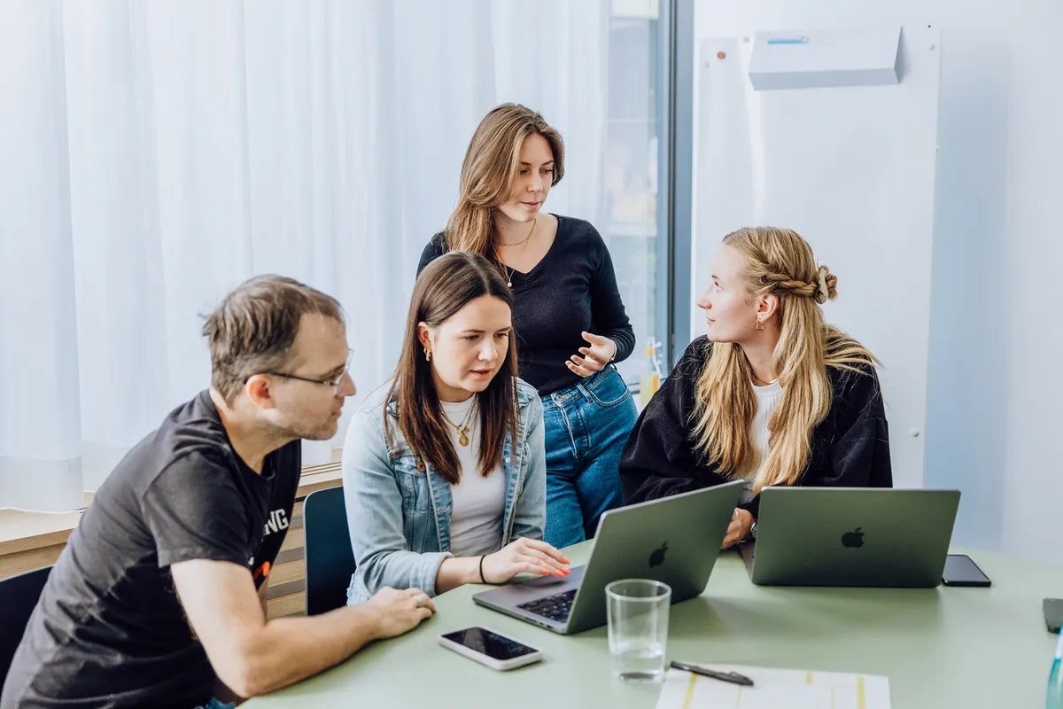Ein Team diskutiert gemeinsam an Laptops über Automatisierungsprozesse